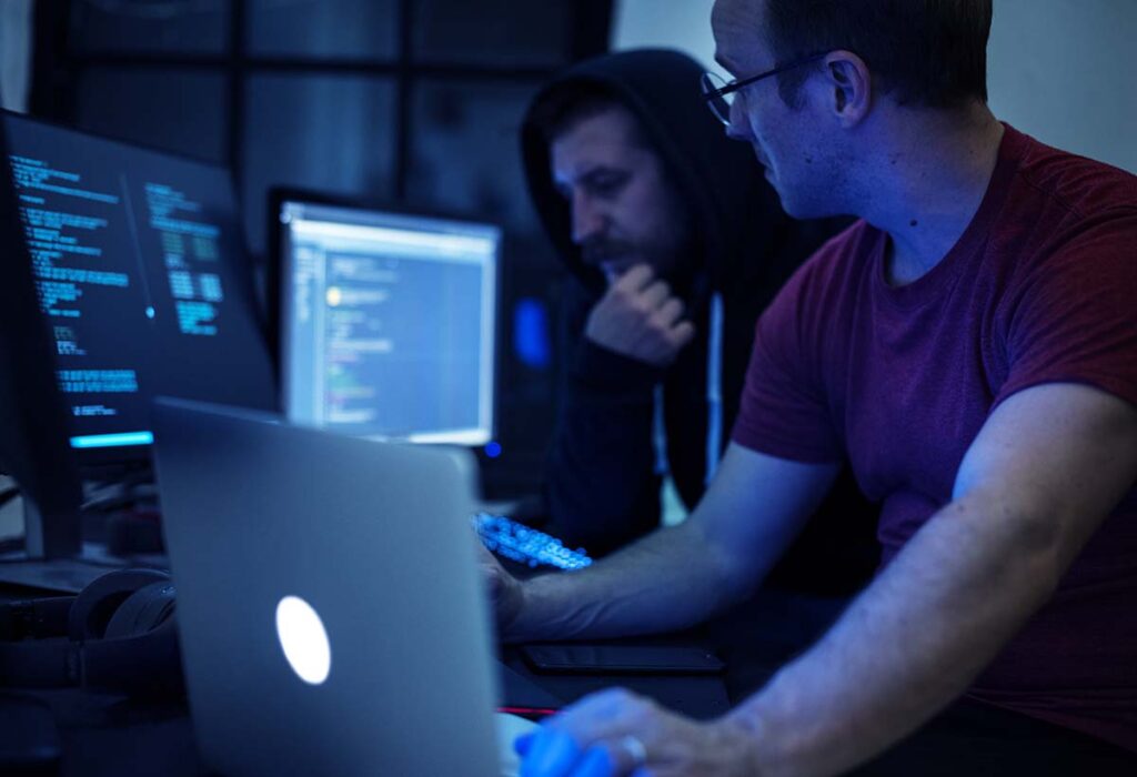 A imagem mostra dois homens mexendo em diversos computadores.