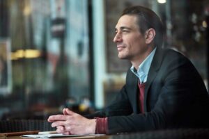 Homem de terno está sentado em uma cadeira de escritório, trazendo o contexto de uma auditoria de compliance.