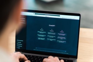Uma pessoa digitando no teclado do notebook enquanto a tela apresenta informações gerais sobre o ChatGPT.