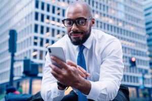 Homem negro utilizando celular para pesquisar sobre Core Banking.