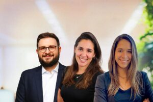Duas mulheres e um homem sorrindo em um ambiente corporativo, trazendo o contexto da cultura de compliance.