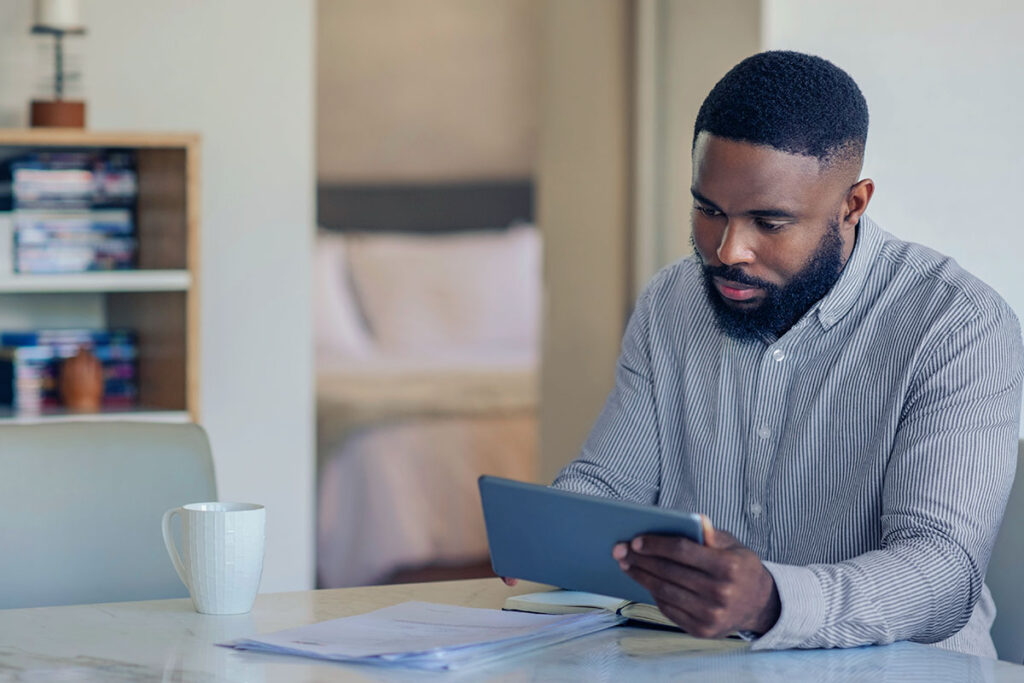 Homem negro utilizando um tablet para pesquisar sobre beyond banking.