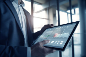 Mãos de um homem mostrando a tela de um tablet com gráficos que apresentam dados de investimentos de risco.