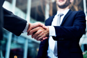 Duas mãos masculinas cumprimentando-se, trazendo o contexto de como fidelizar clientes mais rentáveis para as instituições financeiras.