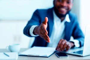 Homem negro estende a mão trazendo o contexto de negociação com uma empresa que oferece soluções que ajudam a alavancar as vendas B2B com o apoio de estratégias de growth marketing.