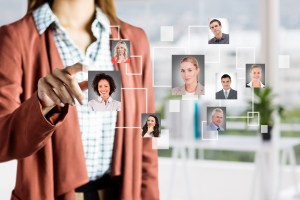 A mão de uma mulher aponta para a foto de uma outra mulher, a qual está conectada a outras pessoas, representando a hipersegmentação de clientes em empresas B2B.