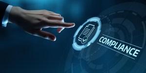 O dedo indicador de uma mão masculina aponta para um botão virtual com um ícone de documento acompanhado do termo "compliance", trazendo o contexto da análise de compliance.