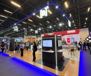 Estande da B3 no 33º Congresso & Expo Fenabrave 2025, o qual possui mesas e cadeiras com várias pessoas passando e, ao fundo e ao lado, o estandes das empresas C6 Bank e Honda.